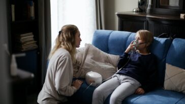 A boy sitting on a couch, wearing a respirator mask. Concept for asthma.