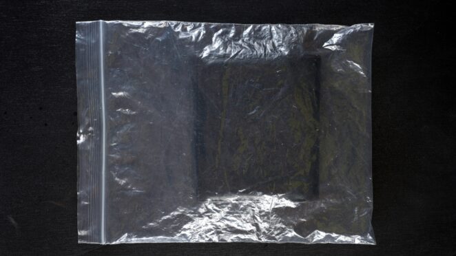 Leather wallet sealed in a plastic bag on a dark surface