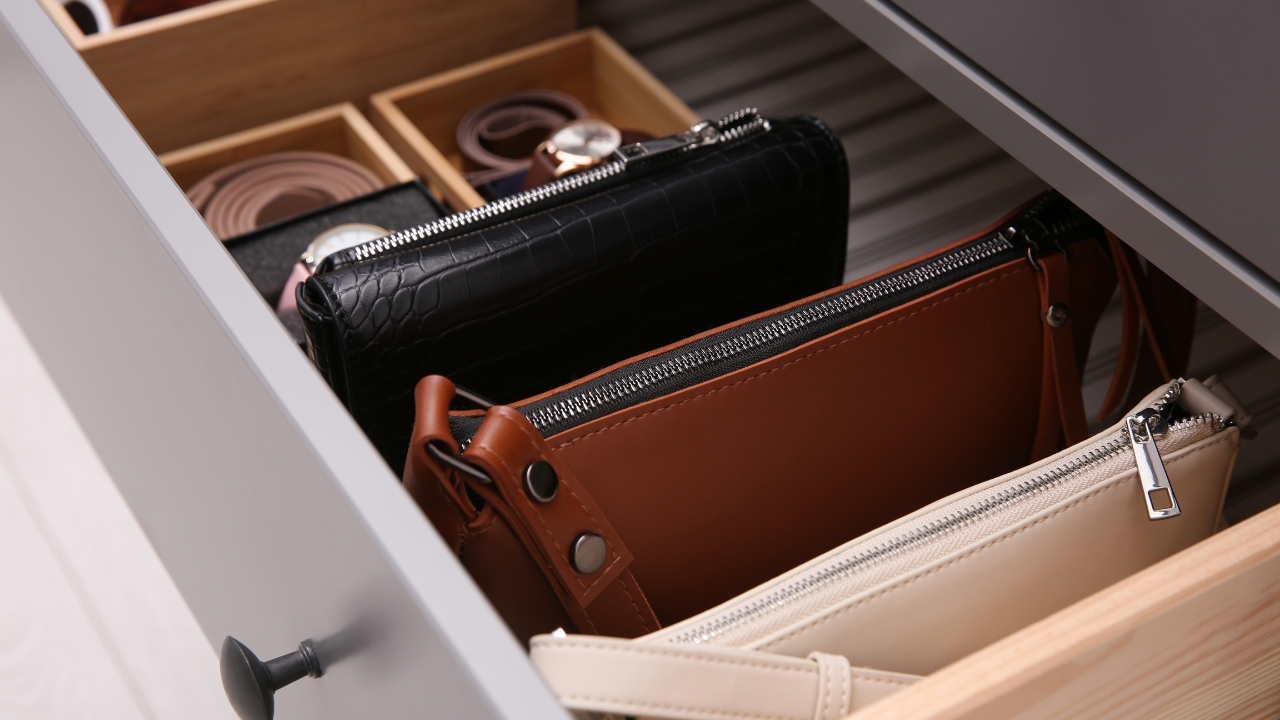 Leather goods neatly stored in a drawer with compartments for wallets, belts, and small accessories