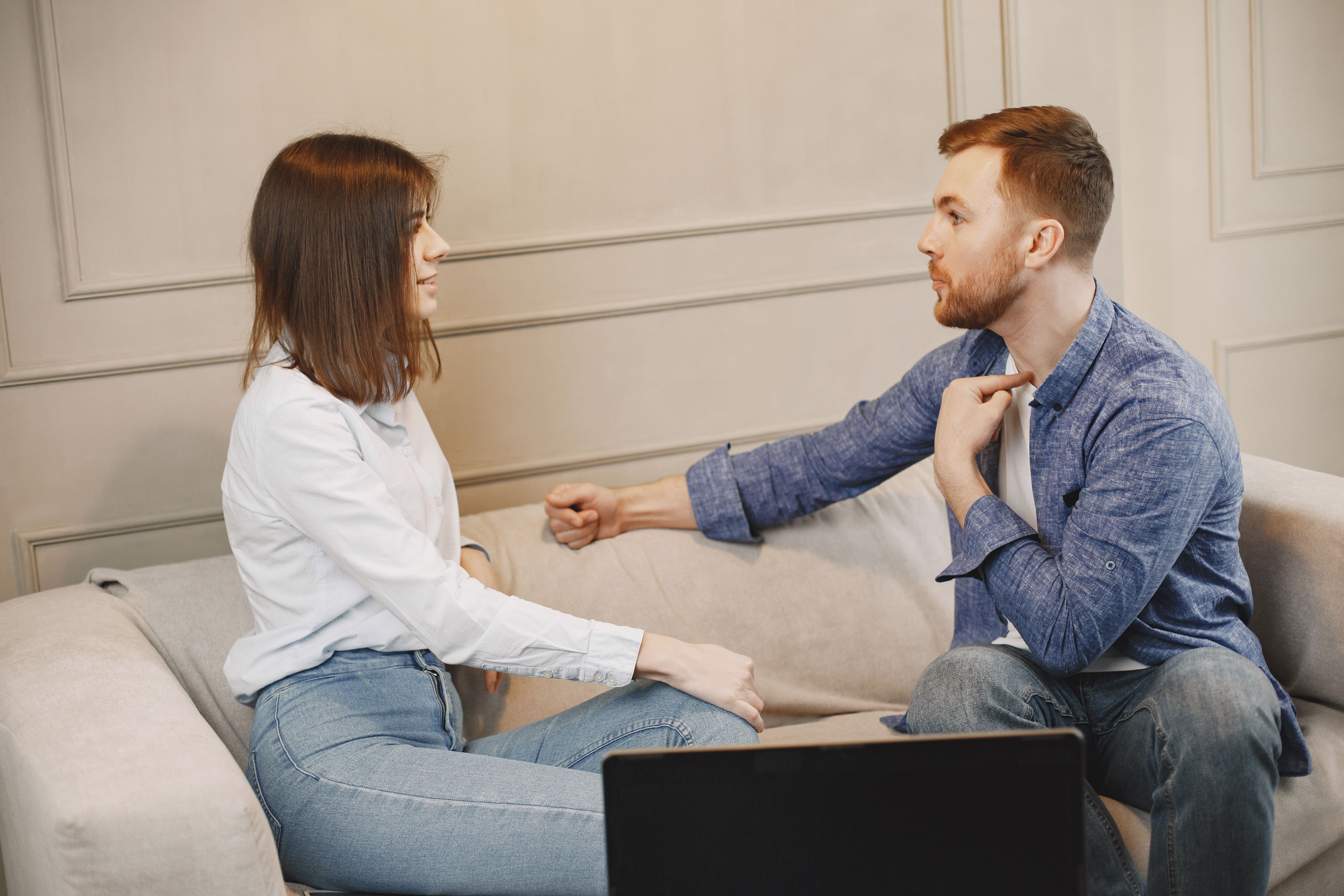 Young couple sitting close on a couch and engaged in a face-to-face conversation