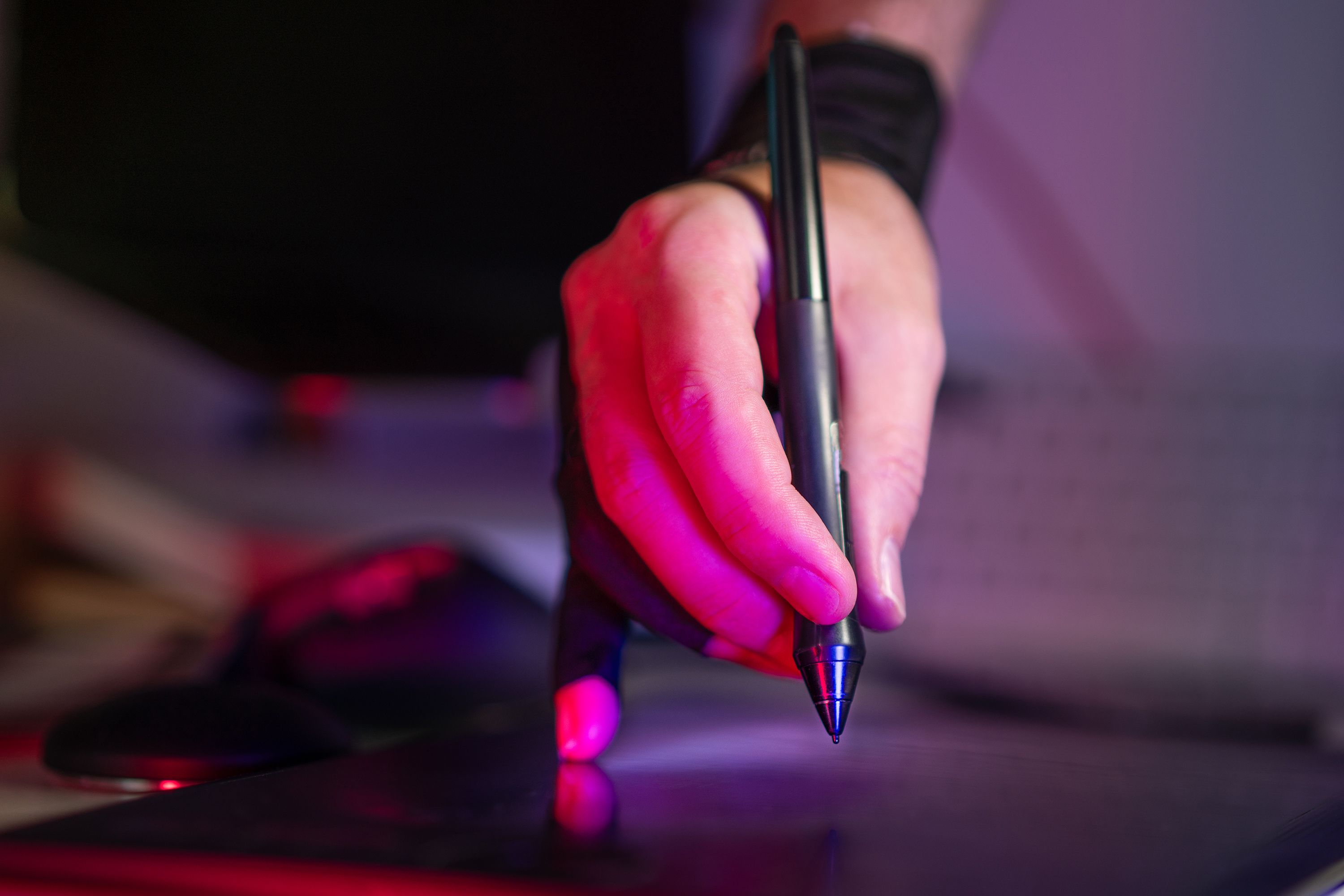 Digital artist using a graphics tablet and stylus to edit images in a creative studio