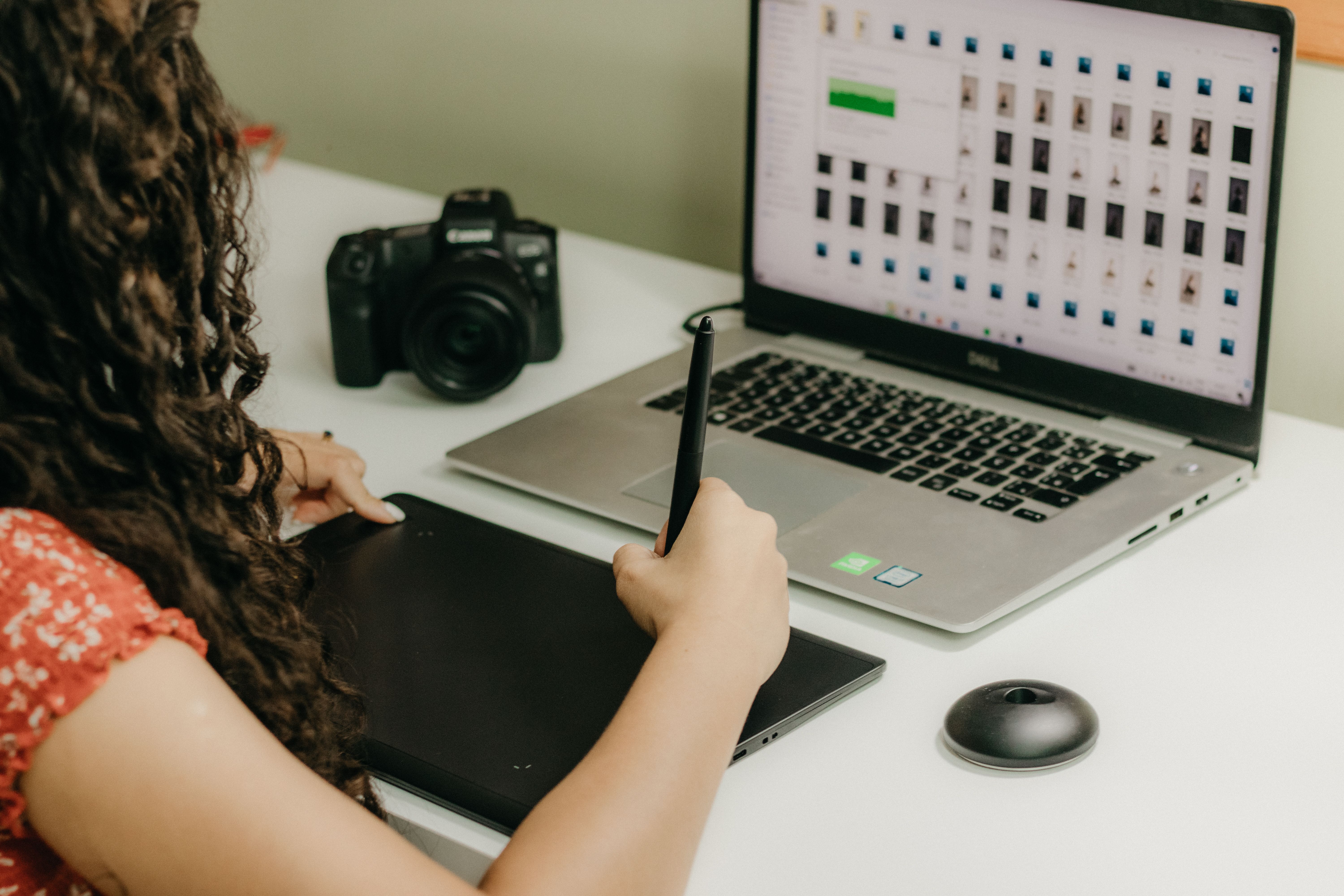 Woman using a graphics tablet and laptop to review and edit photos